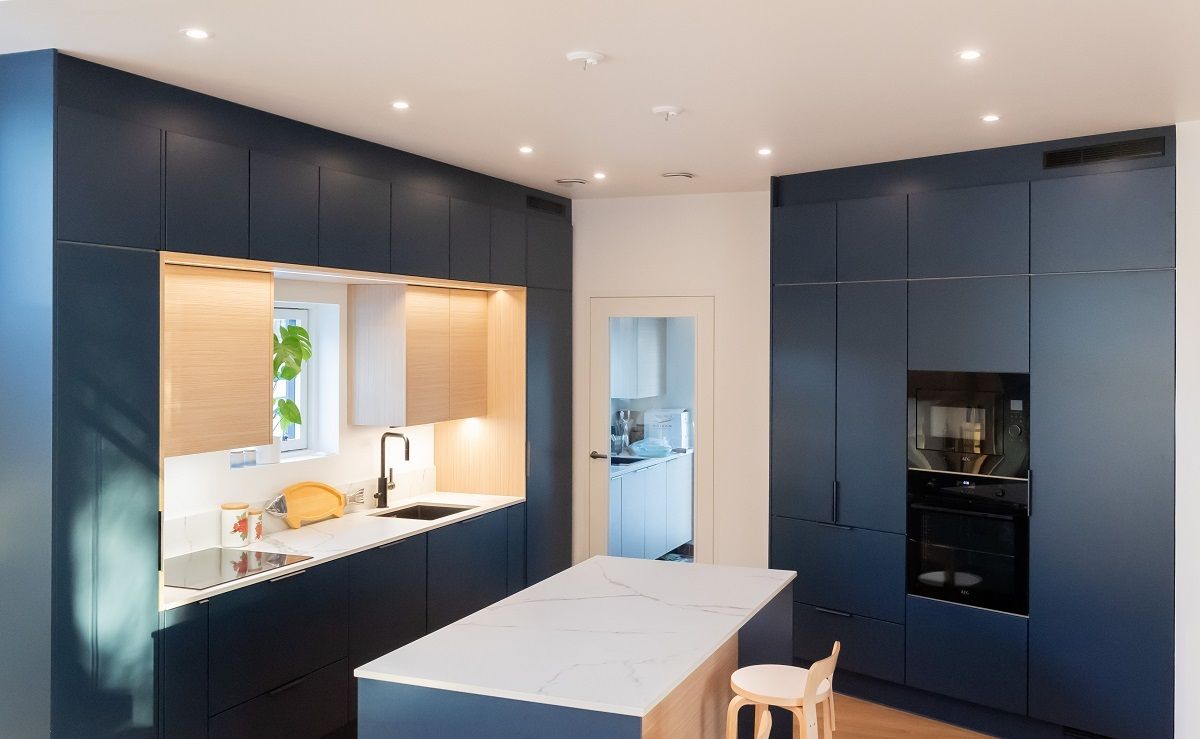 I faretti a soffitto della cucina a vista sono disposti in cerchio davanti agli armadietti su due pareti.